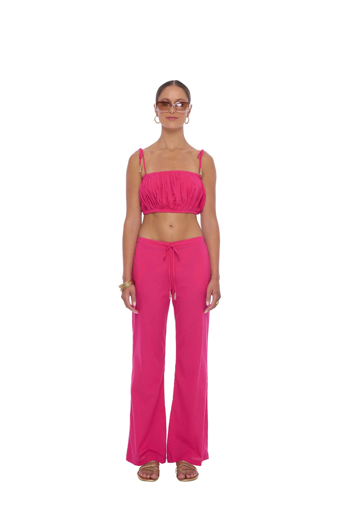 Trendy Demi Crop Top in soft Cotton Voile fabric featuring a ruched design with elasticated details, adjustable tie straps adorned with hand-beaded tassels and side zip closure. Perfect for a modern, casual look